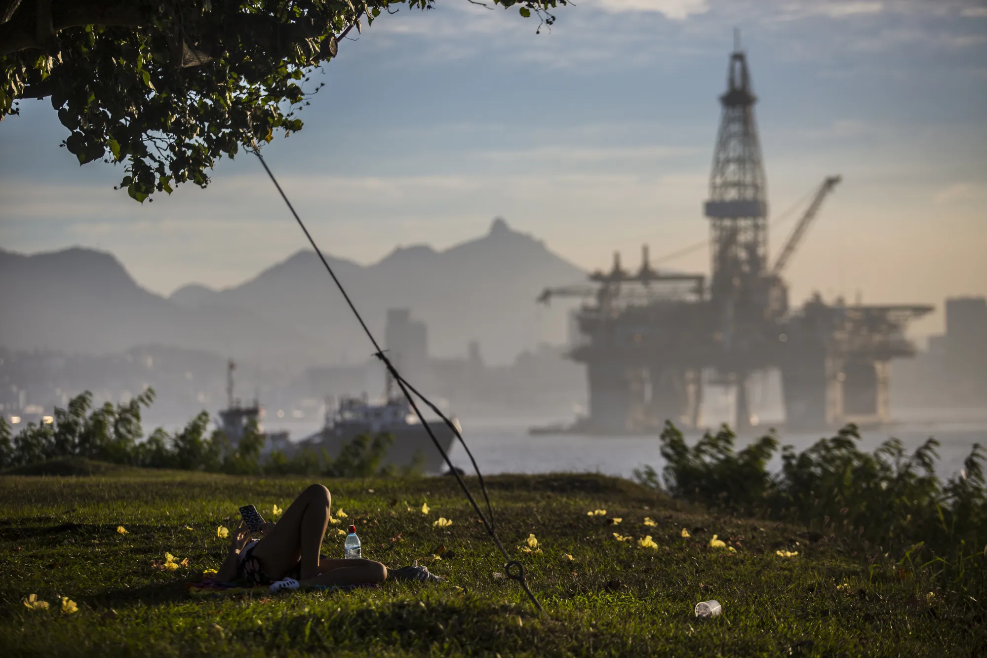 A person lays down on the coast in front of an offshore oil platform near Niteroi, Rio de Janeiro state, Brazil.