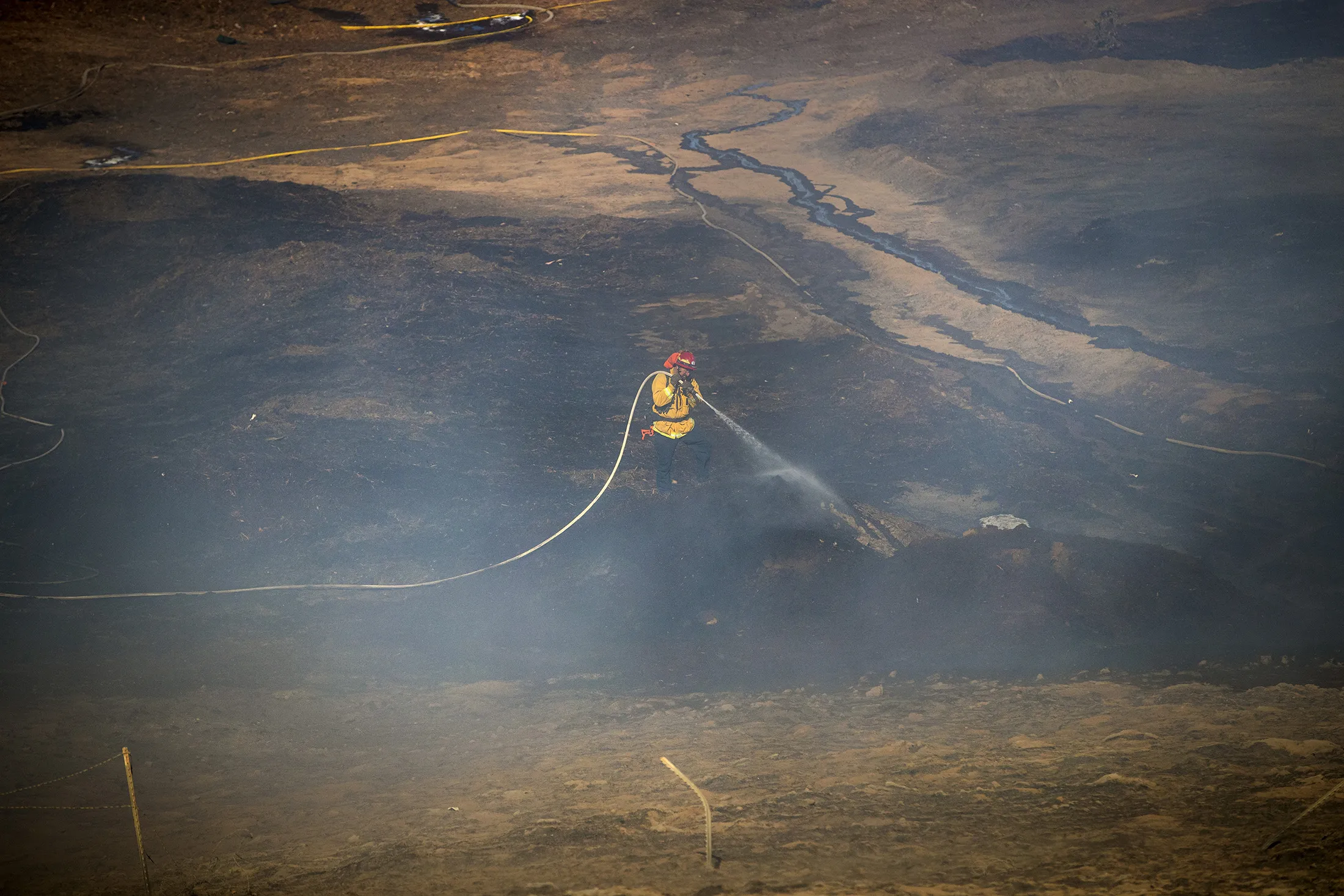 A Riverside firefighter douses hot spots at the Arlanza fire which forced residents off Valley Drive to temporarily evacuate in Riverside, California,&nbsp;on Nov.&nbsp;25.