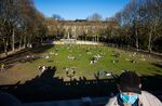A man wearing a protective face mask keeps away from sunbathers scattered on the grass in the park next to Schoeneberg town hall in Berlin on April 18, 2020.