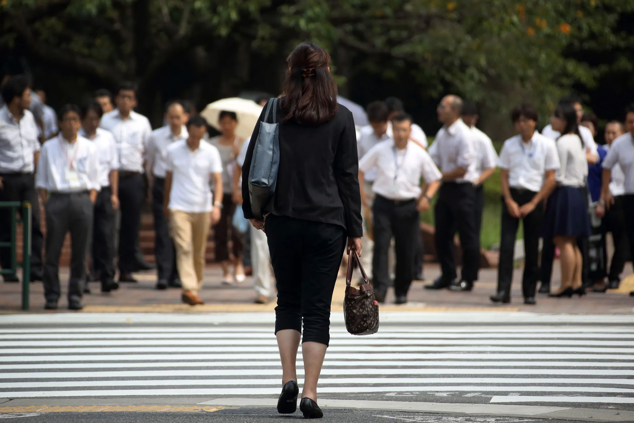 A woman waits to cross a road in the Kasumigaseki area of Tokyo, Japan.
