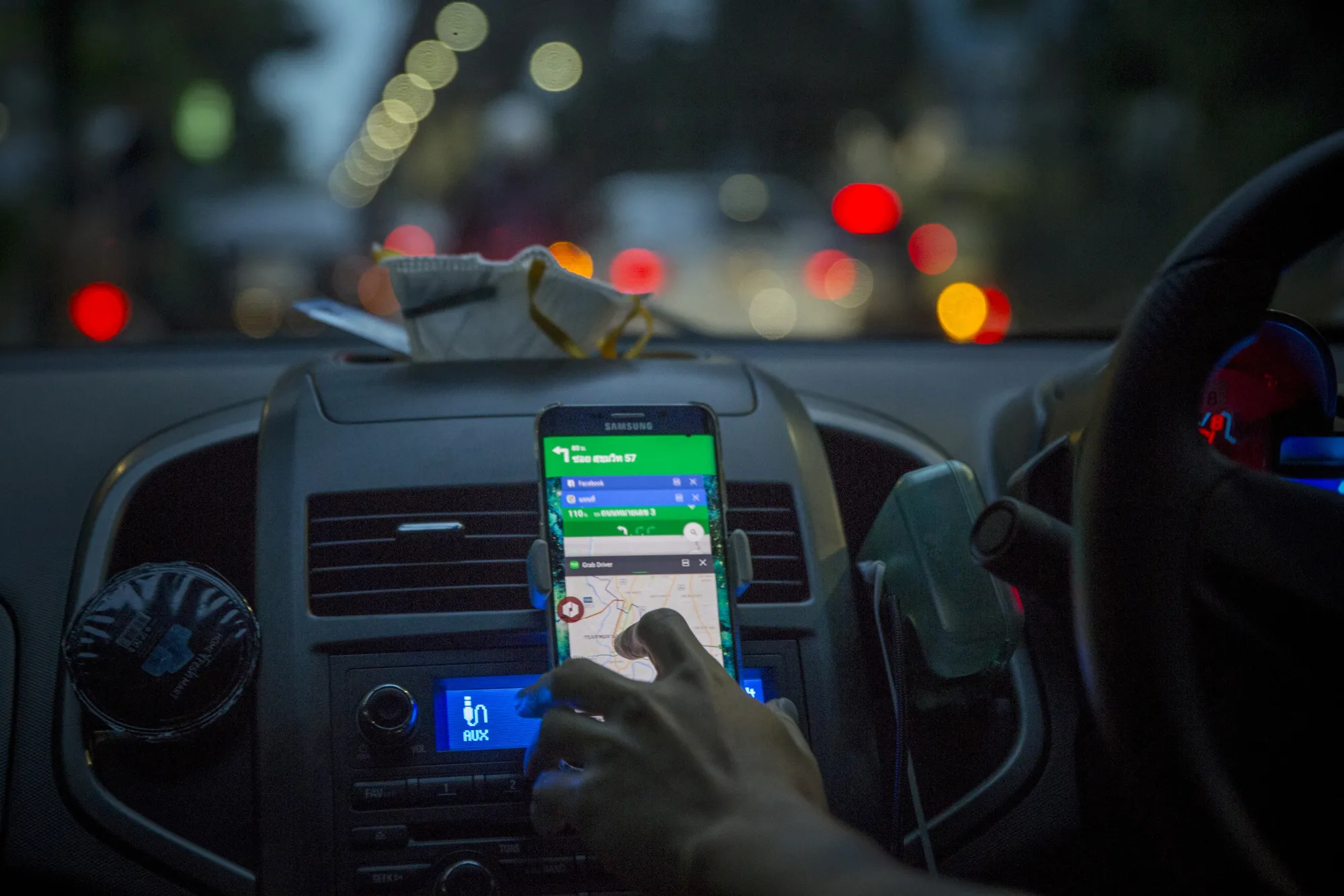 A driver uses the Grab application on a smartphone in Bangkok.