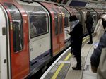 A woman wearing a face mask waits to board an underground train on the Central Line at Bank station in London.