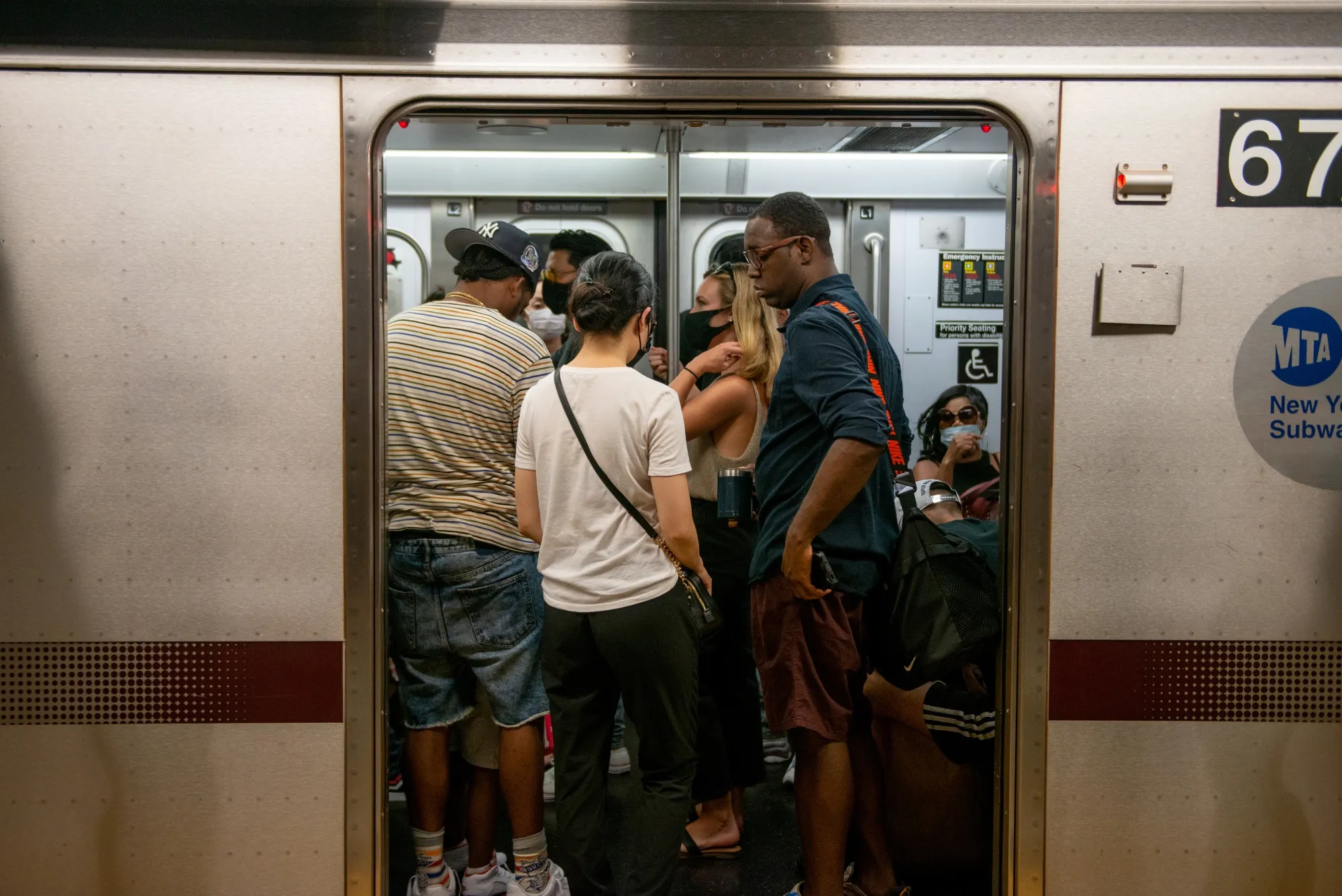 People with and without masks ride on a crowded New York City subway car on July 25, 2020. Mayor&nbsp;Bill de Blasio has urged staggered work times and telecommuting to reduce crowding during the pandemic, but service cuts on transit systems across the U.S. could increase crowds for those who rely on public transportation.&nbsp;
