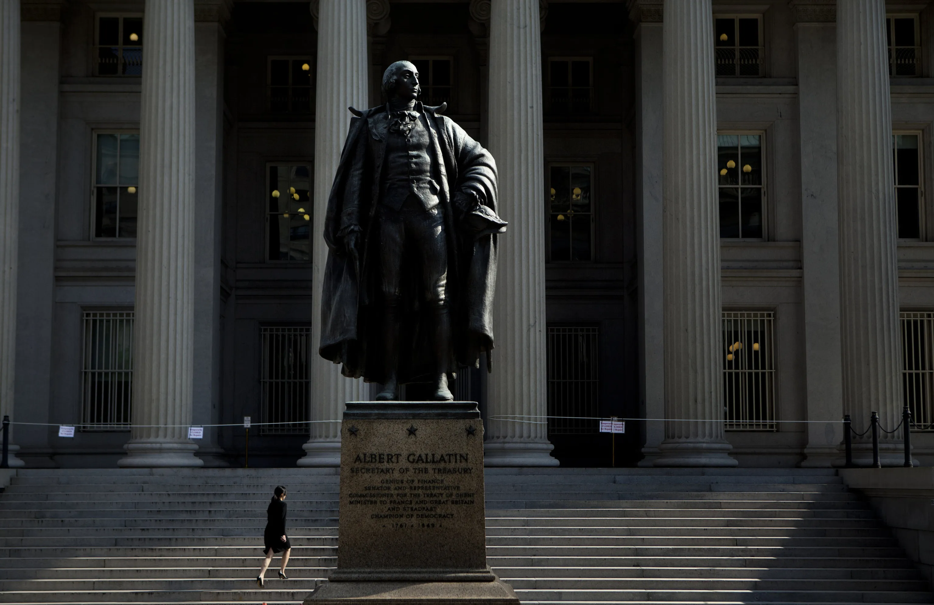 A woman walks past a statue of Albert Gallatin, a long-serving U.S. secretary of the Treasury, that stands in front of the U.S. Treasury building in Washington, D.C.