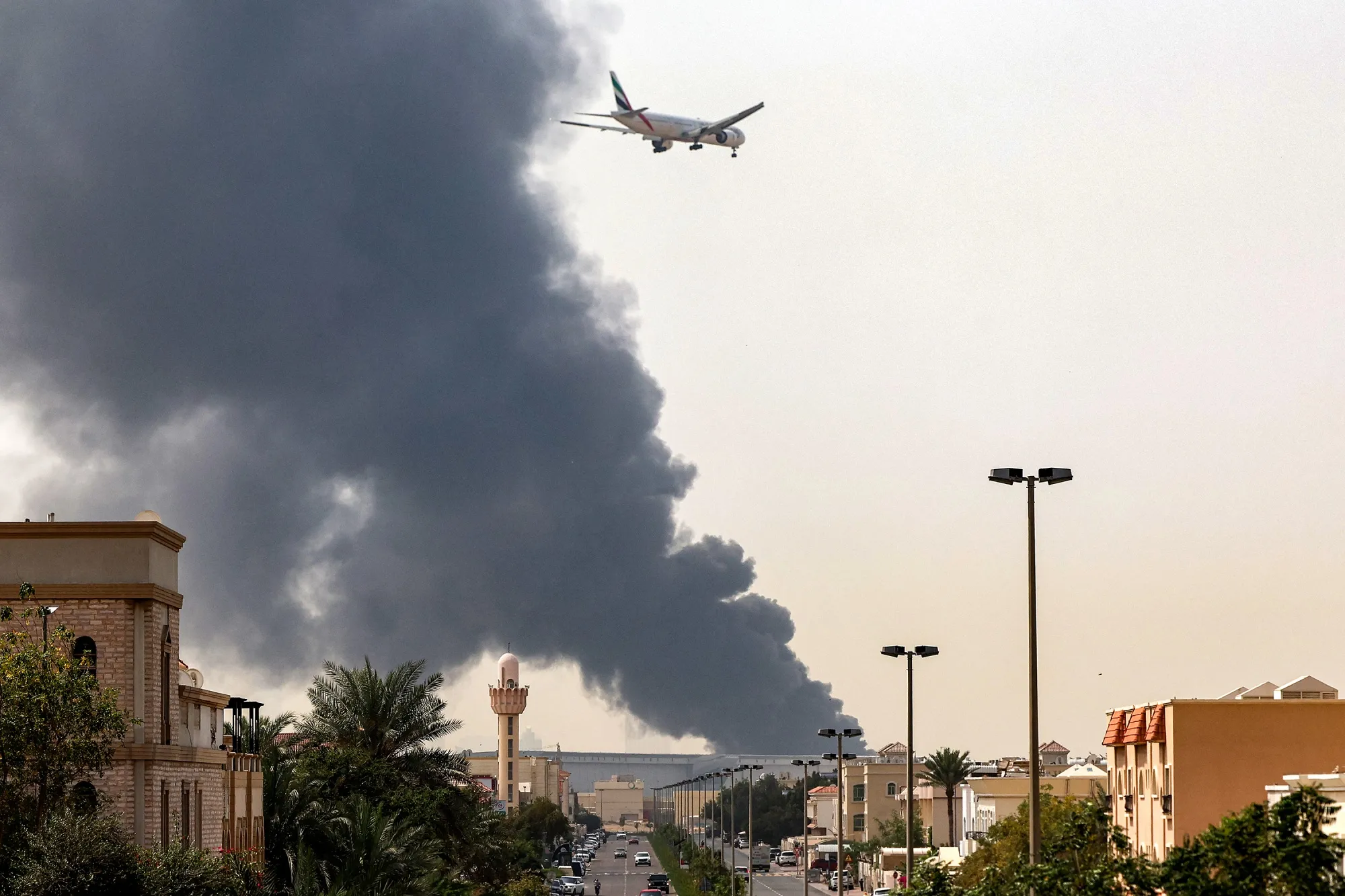 An Emirates aircraft passes smoke from an ongoing fire as it prepares to land at Dubai International Airport, on March 16.
