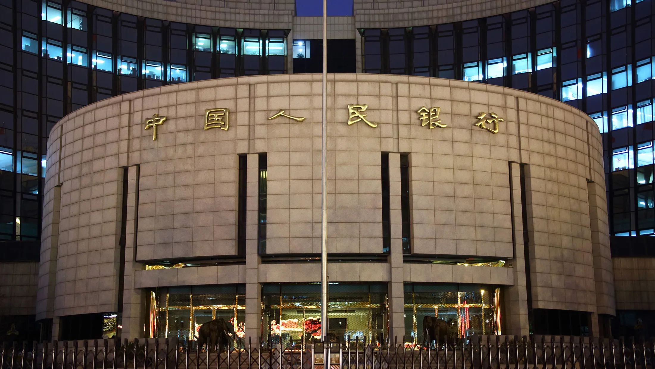 The People's Bank Of China (PBOC) headquarters stand at night in the financial district of Beijing, China, on Monday, March 2, 2015. China's yuan fell to the lowest in more than two years, money-market rates dropped and most stocks advanced after the central bank cut benchmark borrowing costs for the second time in three months amid an economic slowdown.
