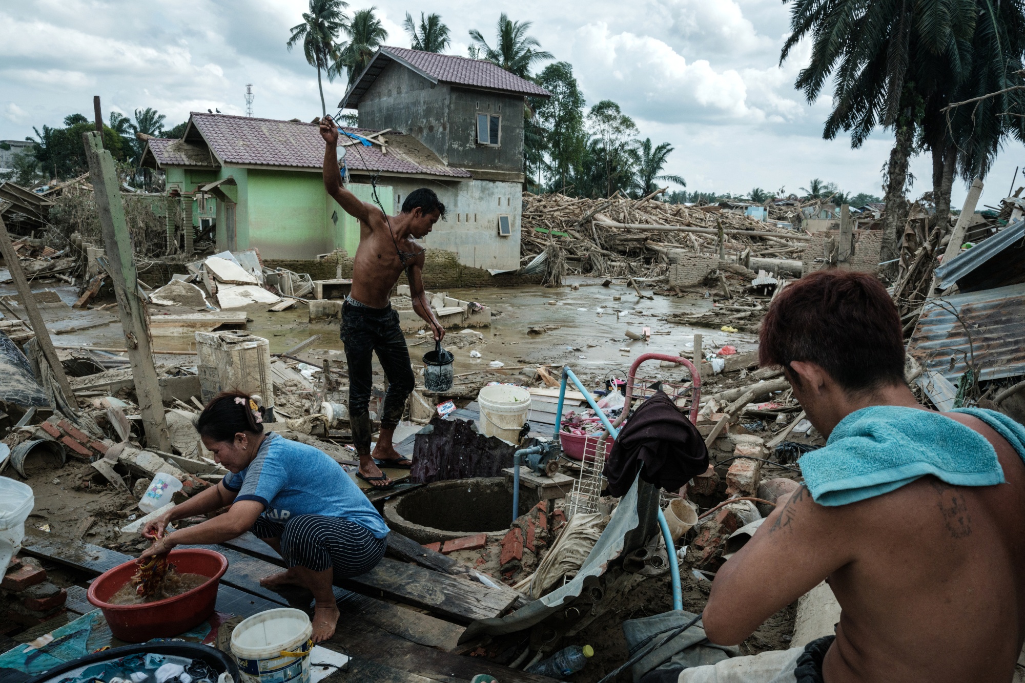 People use water from a well to do their daily chores in an area affected by flash floods in Northern Sumatra, on Dec. 13. Photographer: Yasuyoshi Chiba/AFP/Getty Images