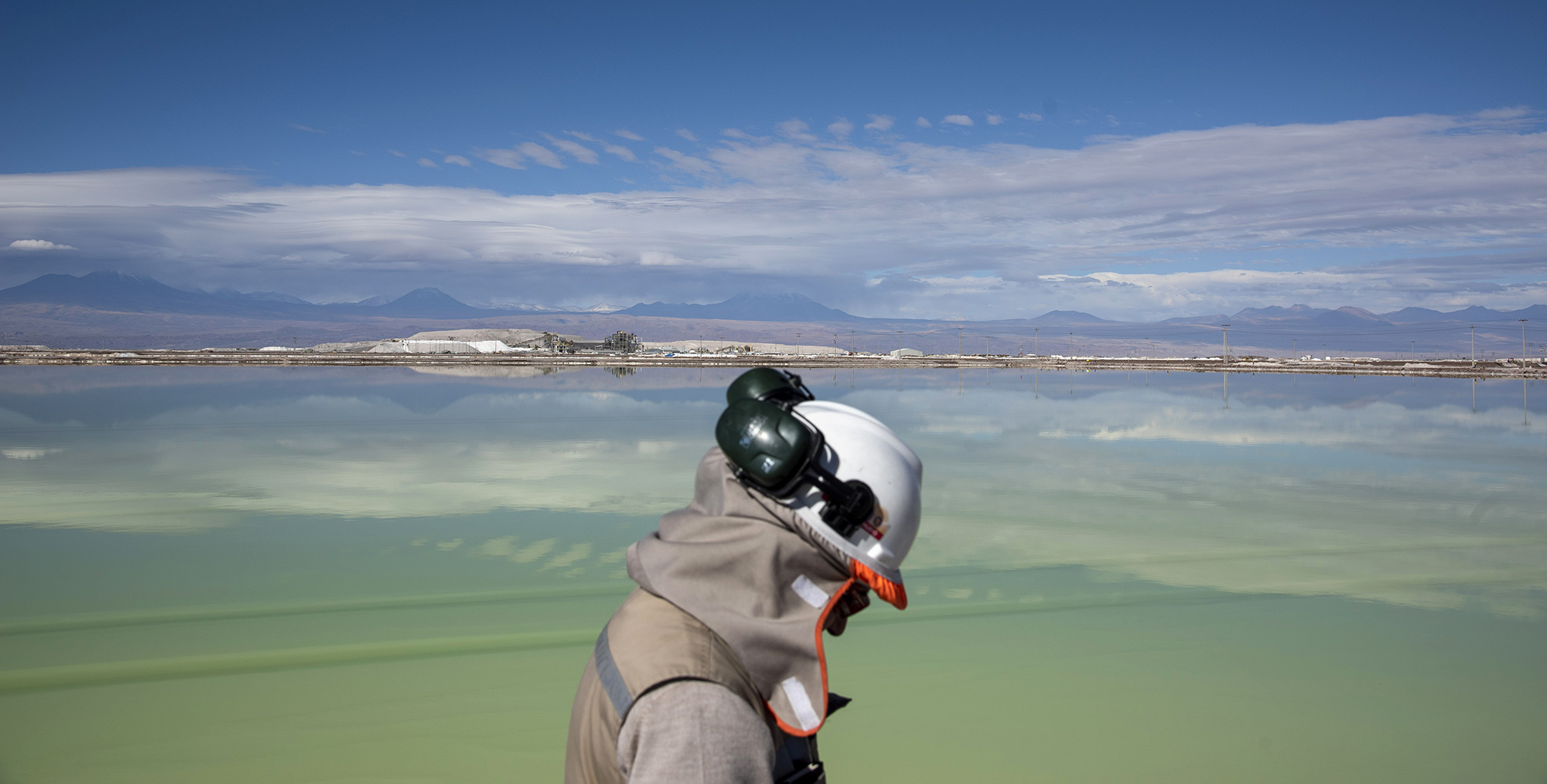 A visitor walks past a brine lake at a lithium mine in the Atacama Desert, Chile.