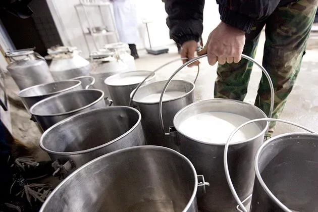 A dairy farmer moves buckets of raw milk at a Nestle SA milk collection center in Shuangcheng, Heilongjiang Province, China, on Jan. 11, 2012