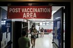 Members of the public walk through the monitoring area after receiving a dose of the Covid-19 vaccine at a vaccination site inside a gymnasium in San Juan City, Metro Manila, the Philippines, on Tuesday, Dec. 28, 2021. 
