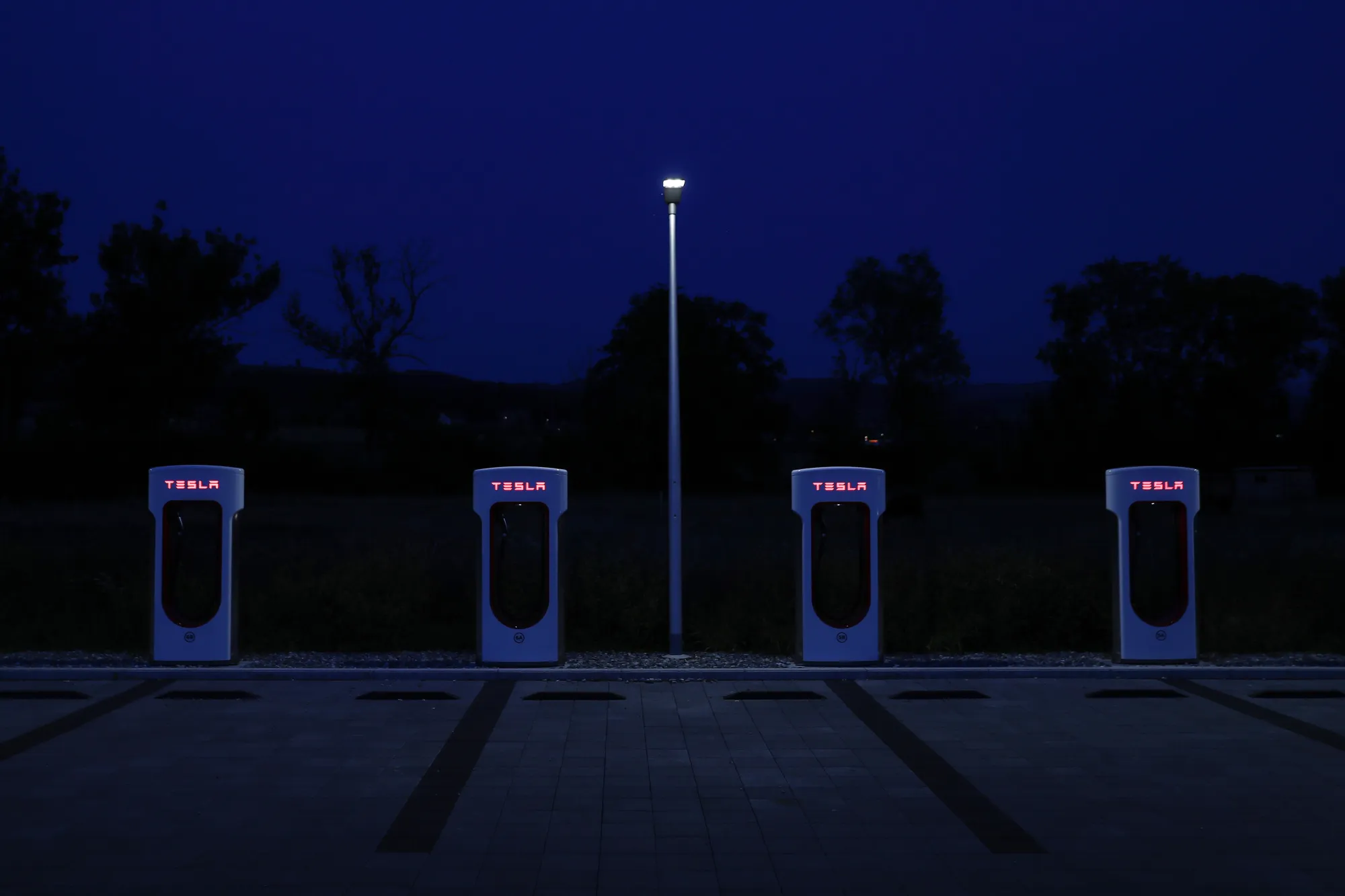 Tesla Inc. Supercharger stations stand illuminated at night in Rubigen, Switzerland.