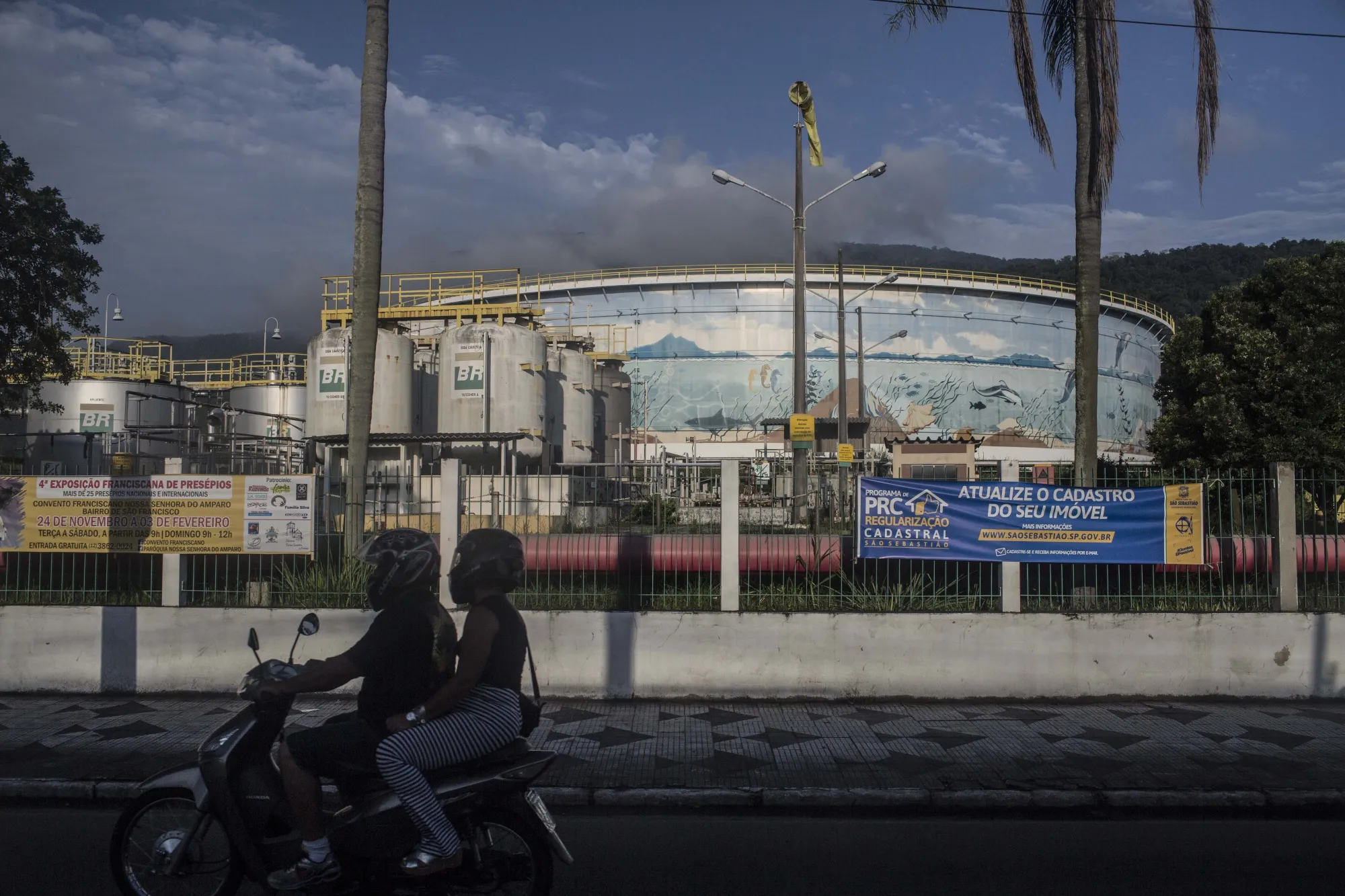 Motorists drive past an oil storage tank at the Petrobras Transporte SA (Transpetro) sea terminal in Sao Sebastiao, Sao Paulo.