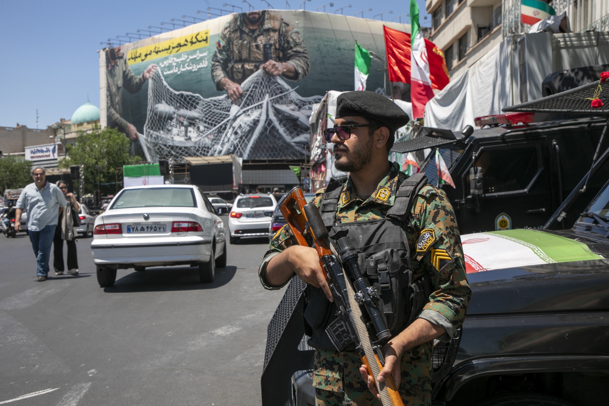 TEHRAN, IRAN - MAY 9: An Iranian police office stands on patrol near a poster depicting Iranian soldiers holding a net in the shape of the Strait of Hormuz, with US military aircraft ensnared in a fishing net, on May 9, 2026 in Tehran, Iran. There is little sign of progress in negotiations between Iran and the United States, despite both sides' insistence that their monthlong ceasefire is holding. (Photo by Majid Saeedi/Getty Images) Photographer: Majid Saeedi/Getty Images Europe