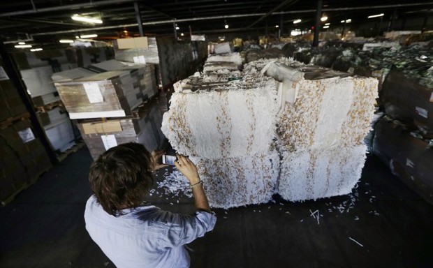 TerraCycle founder Tom Szaky photographs large bales of recycled cigarette butts in a warehouse.