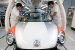 Employees place a windshield on a Volkswagen AG Beetle at the company’s assembly plant in Puebla, Mexico