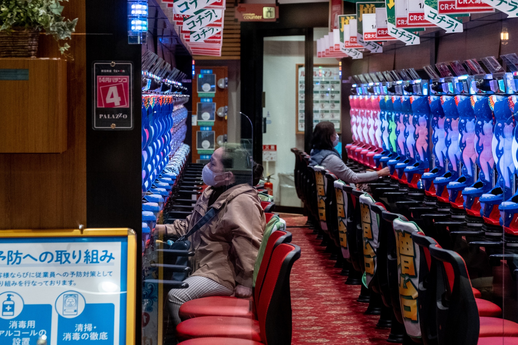 Wanita bertopeng bermain pachinko di Tokyo parloour pada 5 April.