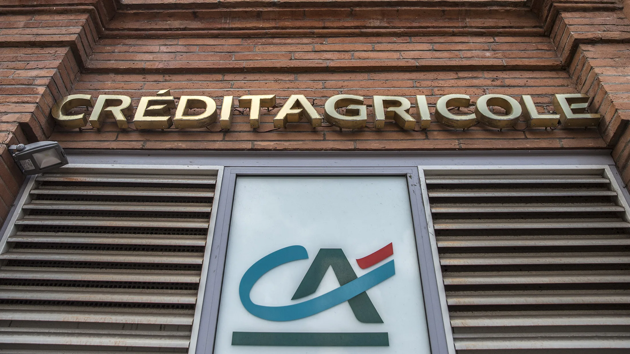 Logos sit on display outside a Credit Agricole SA bank branch in Toulouse, France.
