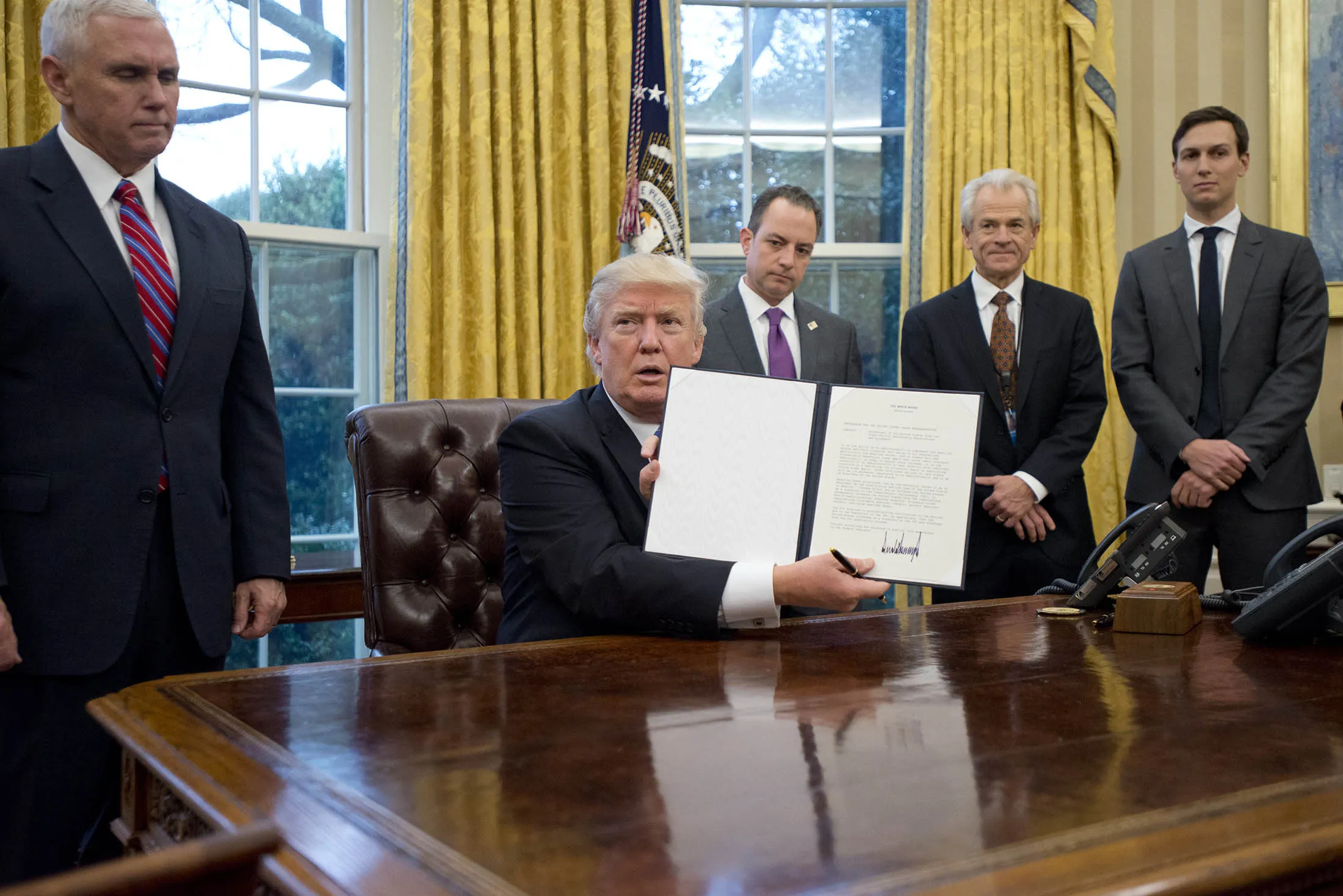 Donald Trump holds up an executive order withdrawing the U.S. from the TPP.
