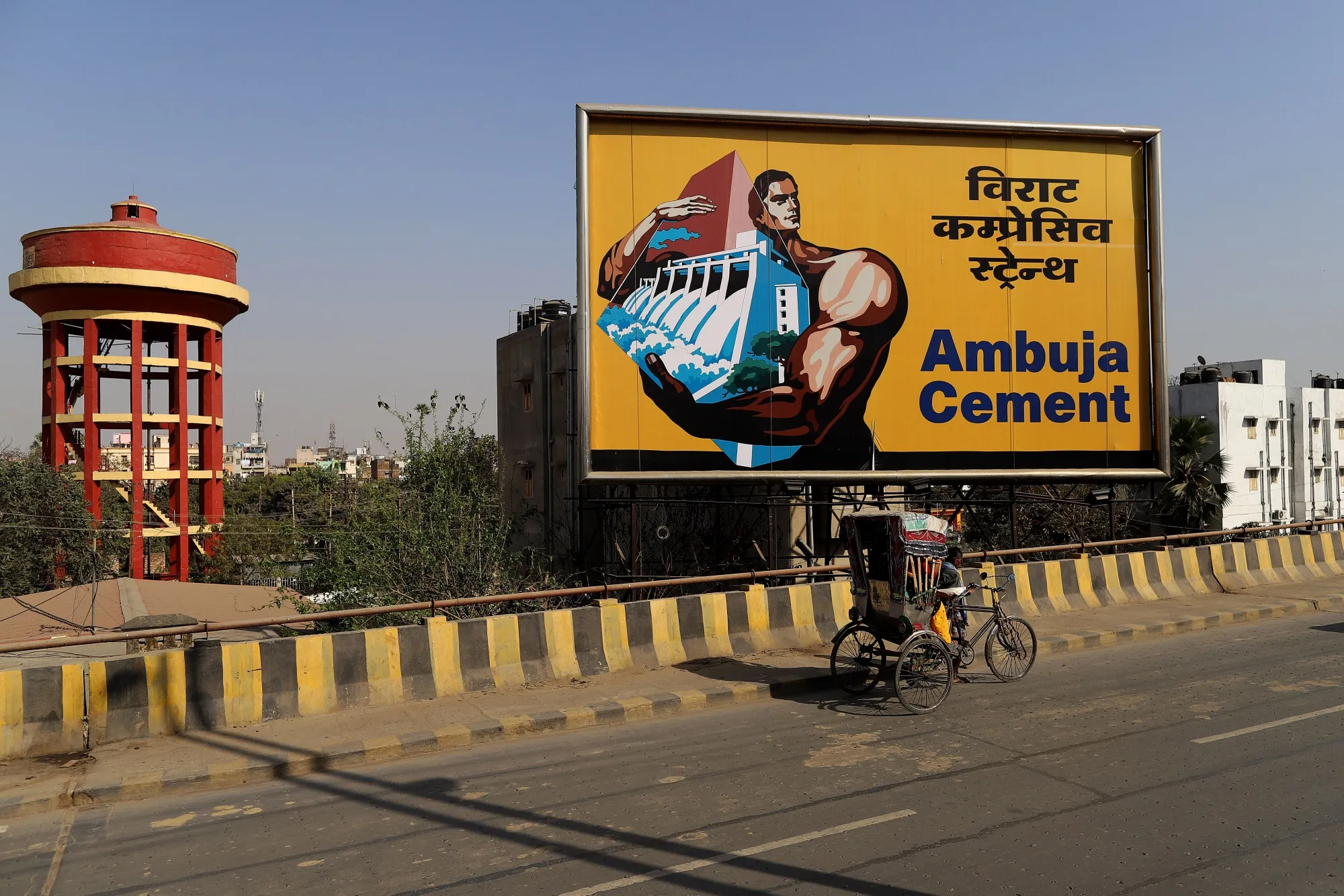 A rickshaw-puller travels past an Abuja Cements Ltd. billboard&nbsp;in Patna, Bihar, India.