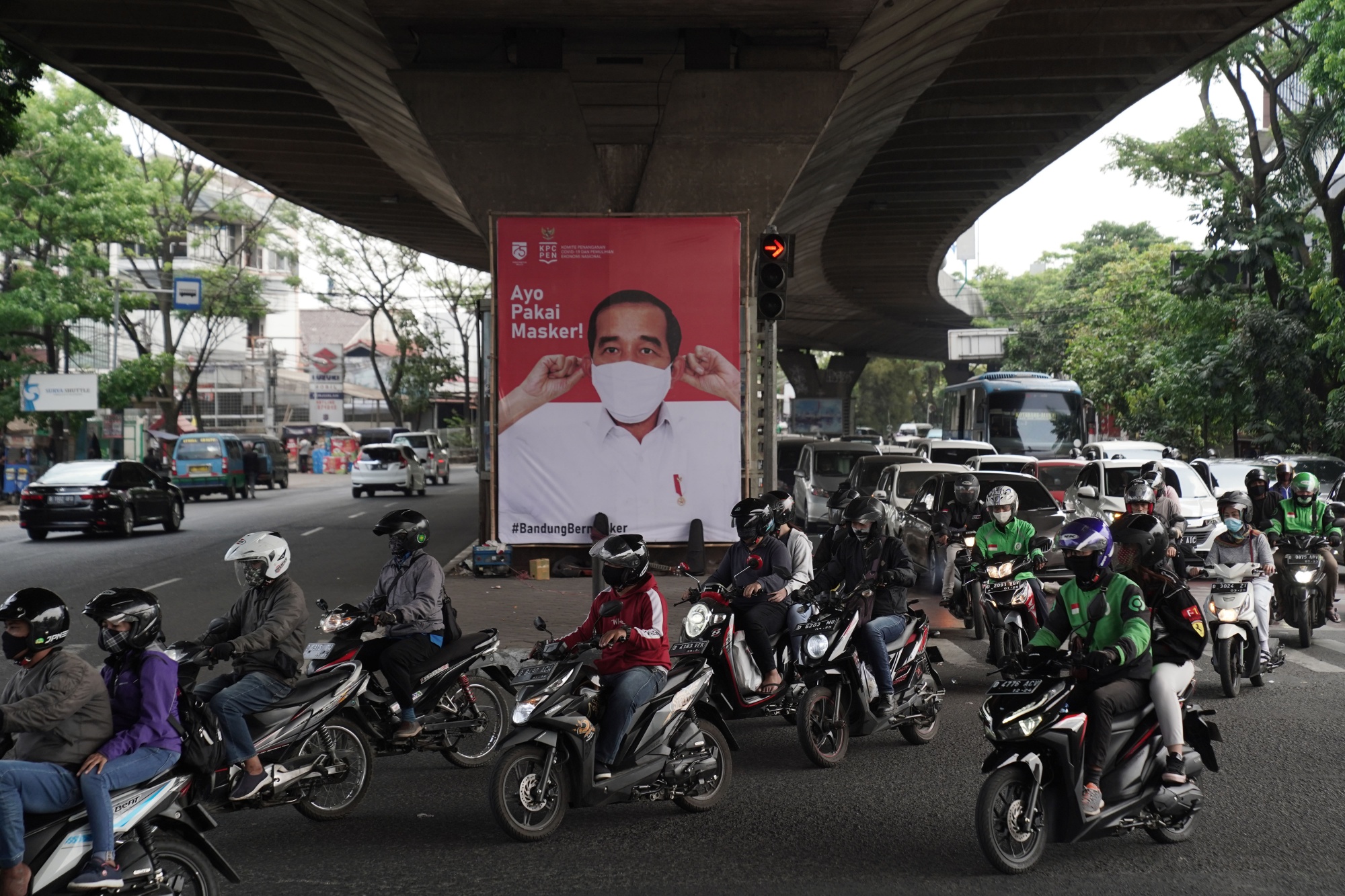 Motorcyclists drive past a poster of Indonesian President Joko Widodo urging people to wear masks in Bandung, in Sept. 2020.&nbsp;