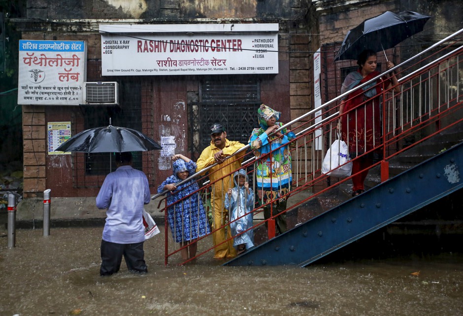 Pedestrians wait to cross a flooded street in Mumbai during heavy rains in June 2015.