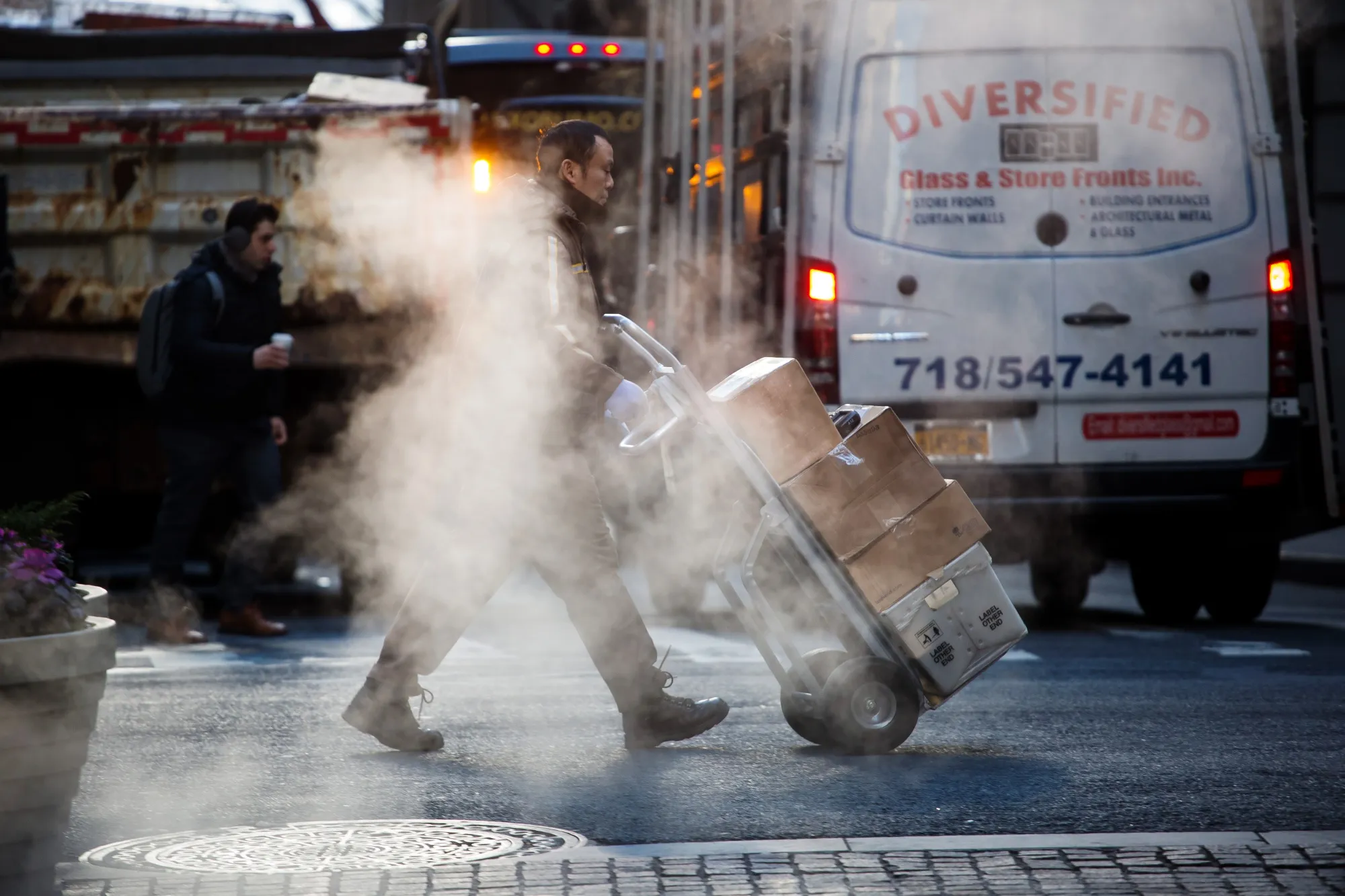 A United Parcel Service Inc. (UPS) employee pushes a dolly of packages across Wall Street&nbsp;in New York.