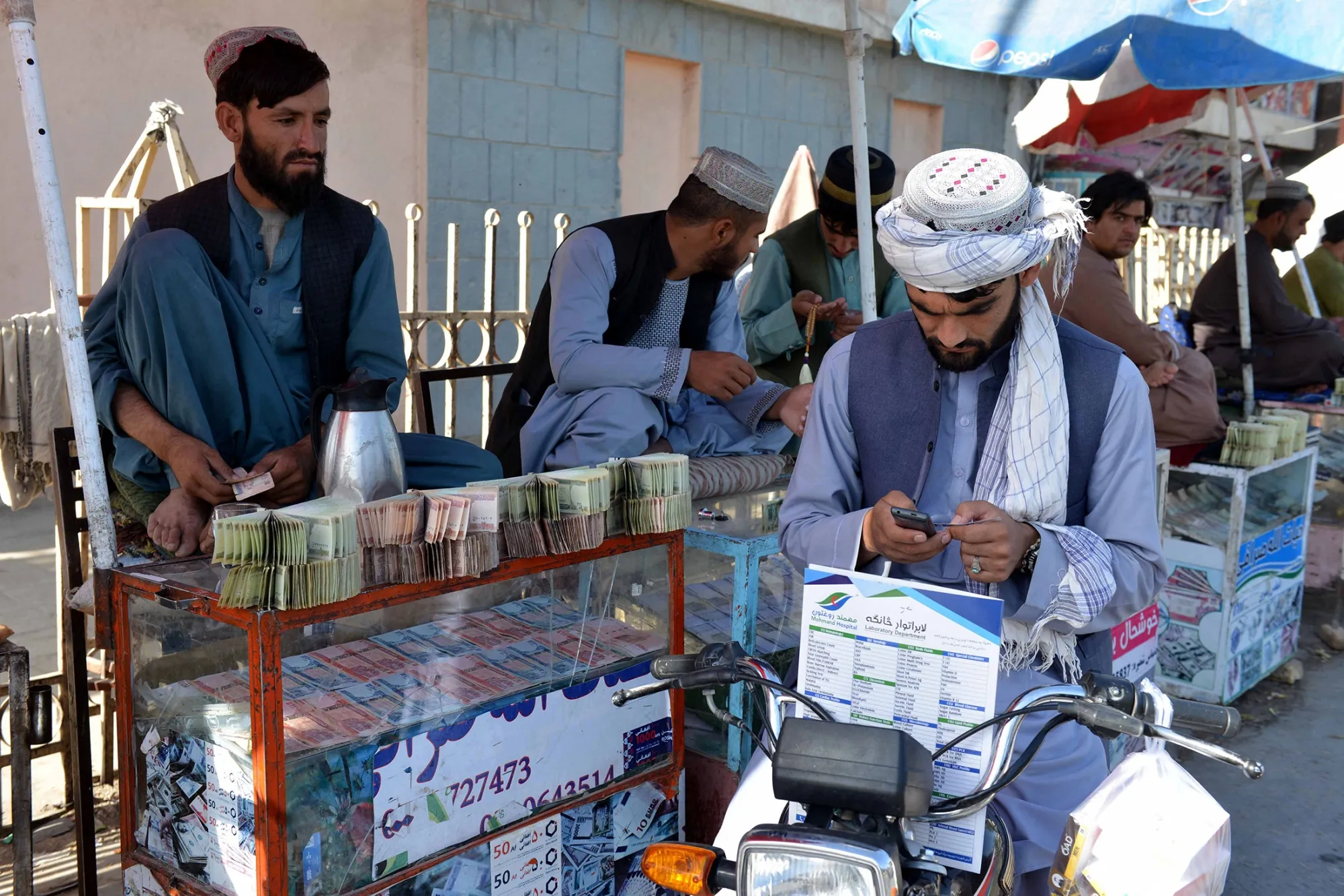Money changers sit at the currency exchange market along a road in Kandahar in September.