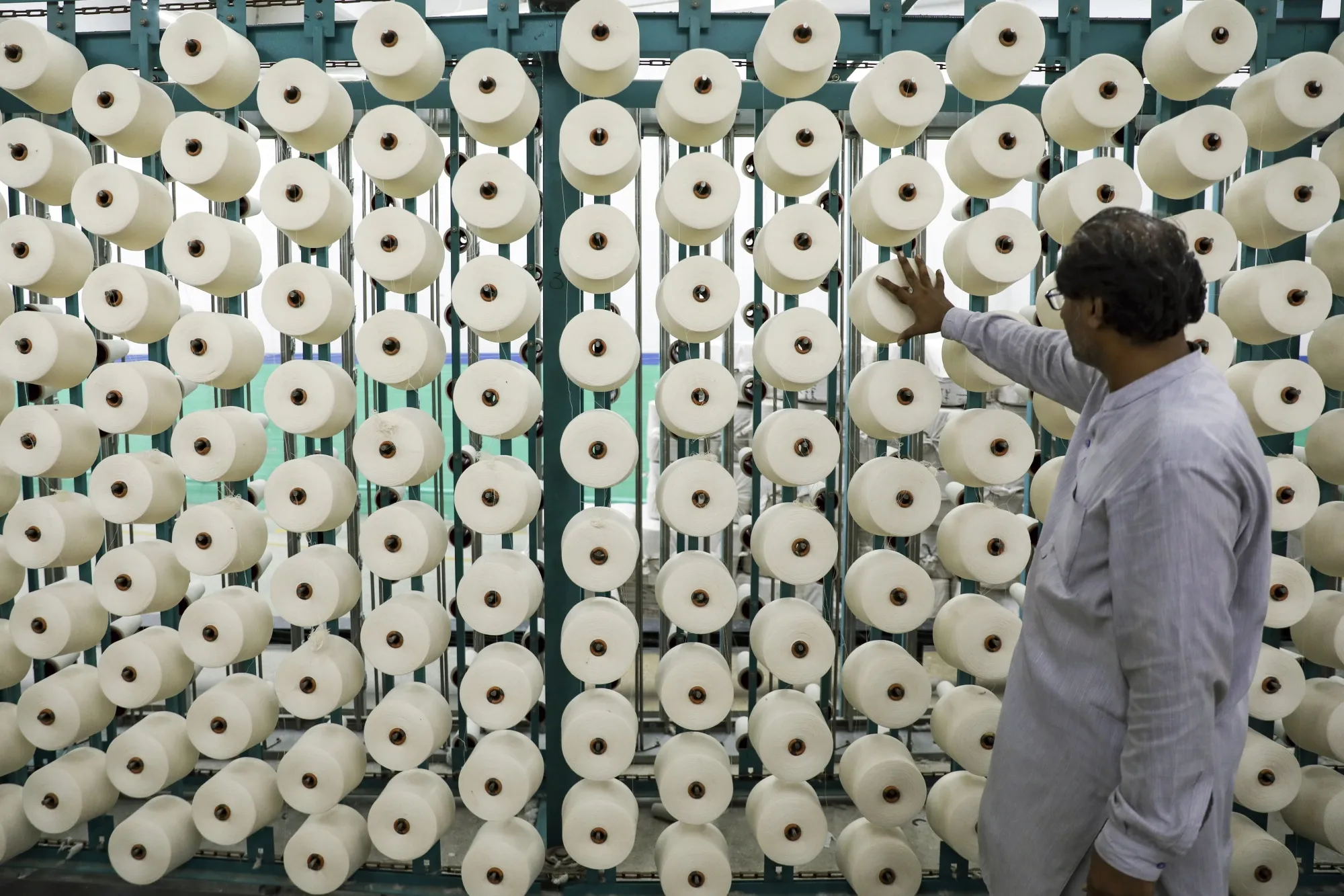 A worker in front of cotton cones at the warping section at a Gohar Textile Mills Pvt Ltd. facility in Faisalabad, Punjab, Pakistan, on Thursday, Sept. 7, 2023.