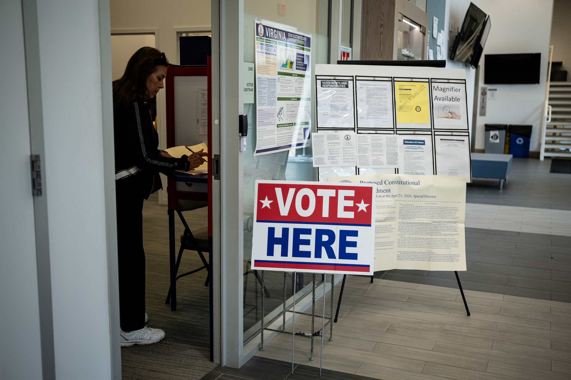 "Vote Here" signage near information posters at a polling location inside Falls Church City Hall during early voting on a proposed constitutional amendment in Falls Church, Virginia, US, on Friday, March 20, 2026. Virginia lawmakers are looking to redraw the state's congressional maps, the latest push by Democrats as the party seeks to counter similar moves by Republicans in the race to win a House majority in the 2026 midterms. Photographer: Graeme Sloan/Bloomberg