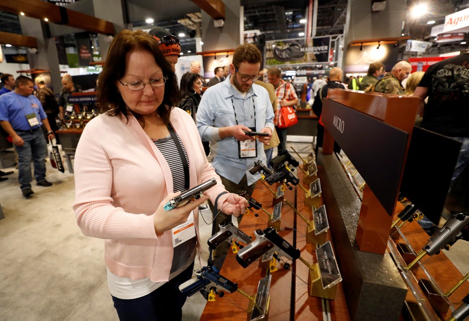 People inspect guns displayed at the SHOT (Shooting, Hunting, Outdoor Trade) Show in Las Vegas in January.
