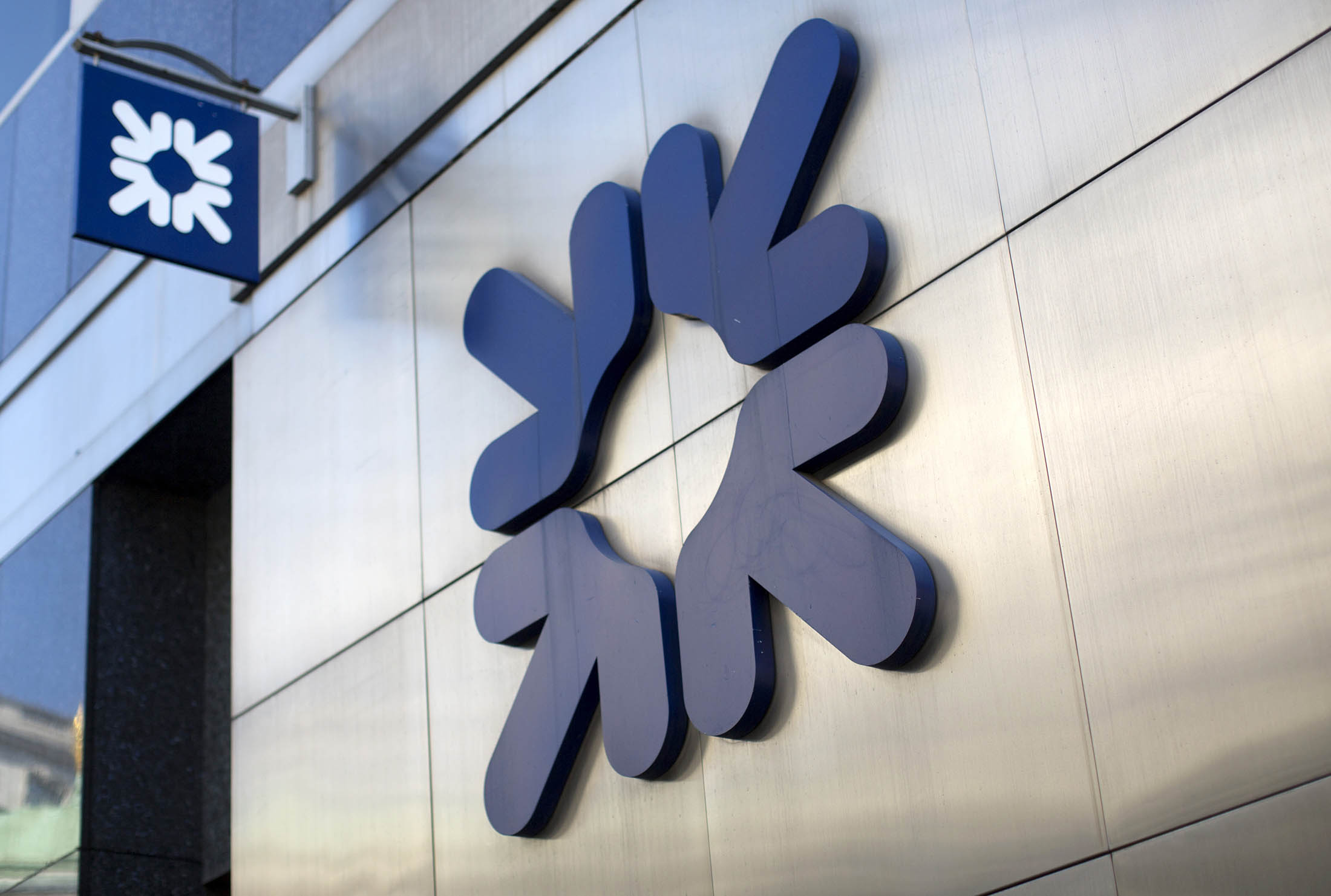 An RBS logo sits outside a Royal Bank of Scotland Plc (RBS) bank branch in London, U.K., on Thursday, June 11, 2015. Chancellor of the Exchequer George Osborne said he'll start returning Royal Bank of Scotland Group Plc to private ownership in the coming months, even though it may cause a loss for U.K. taxpayers.
