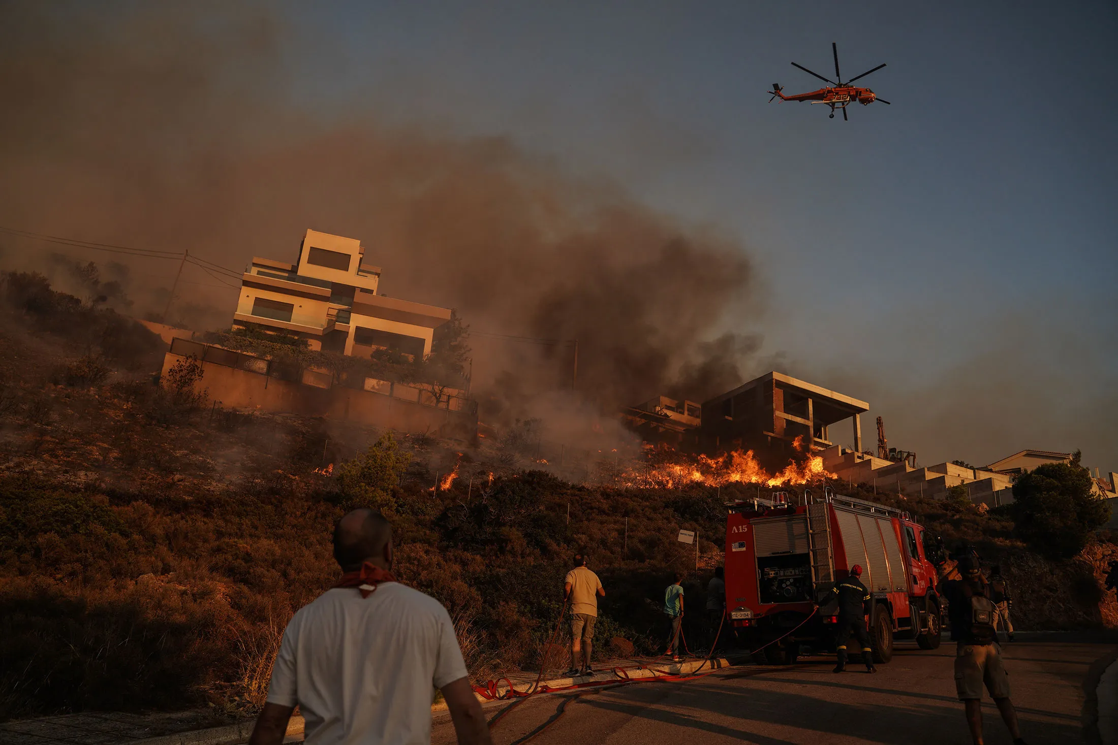 Firefighters and volunteers work to extinguish a burning building during a wildfire in Saronida, south of Athens, Greece, on July 17. Accelerating global warming is narrowing humanity’s choices to successfully slow the worst of the climate crisis.