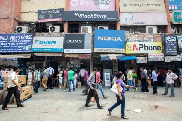 Pedestrians pass in front of smartphone wholesale outlets at Gaffar Market in New Delhi on April 9, 2013