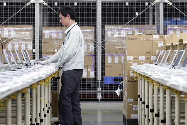 A worker configures the software system and programs on Panasonic laptops at the company's plant in Kobe City, Japan.