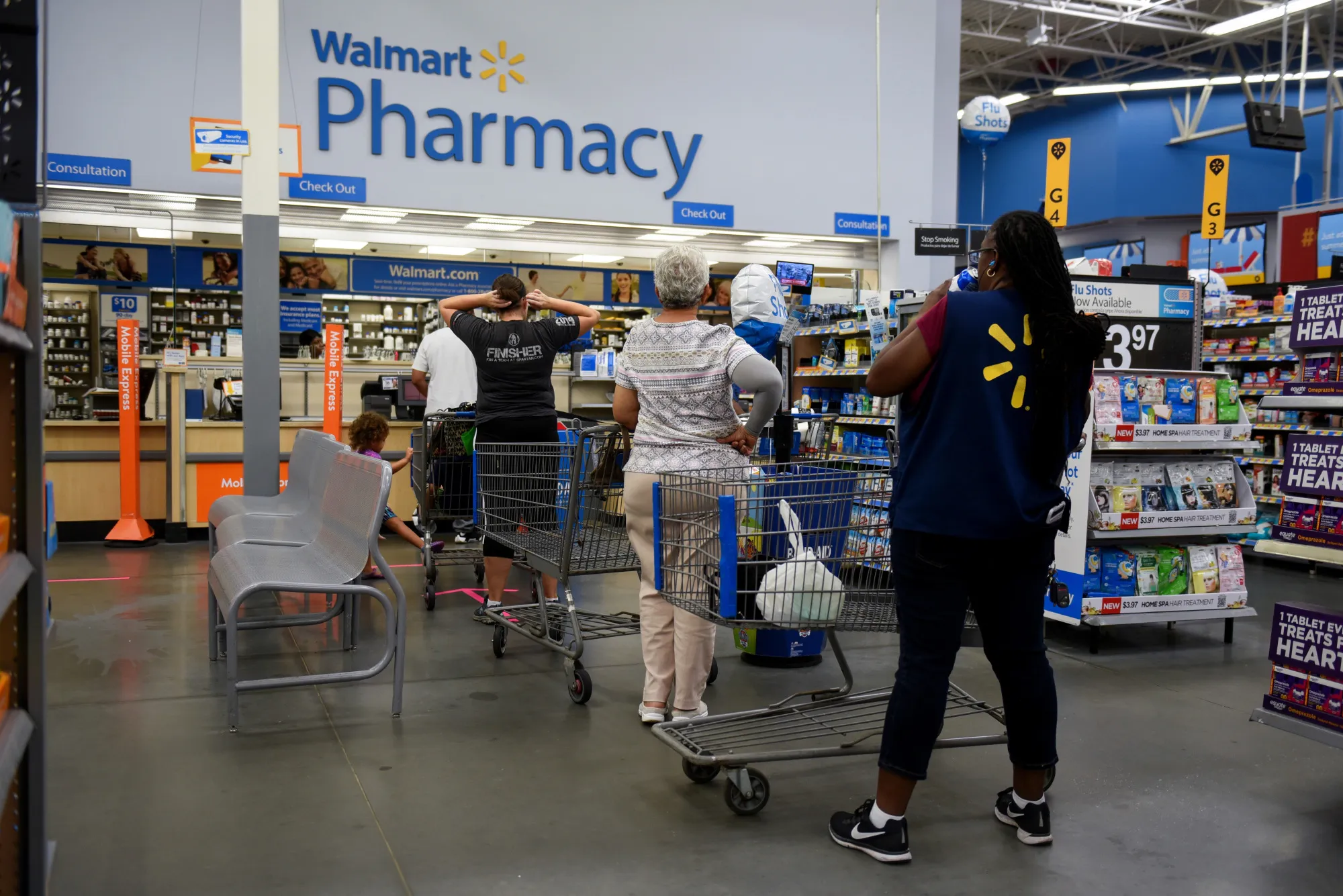 Shoppers wait in line to be served at the pharmacy of a Walmart Inc. store in Charlotte, North Carolina.