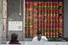 Investors stand in front of an electronic stock board at a securities brokerage in Shanghai, China.
