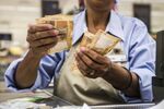 A cashier counts rand banknotes at the check out counter of a store in the Hatfield Plaza shopping center in Pretoria, South Africa
