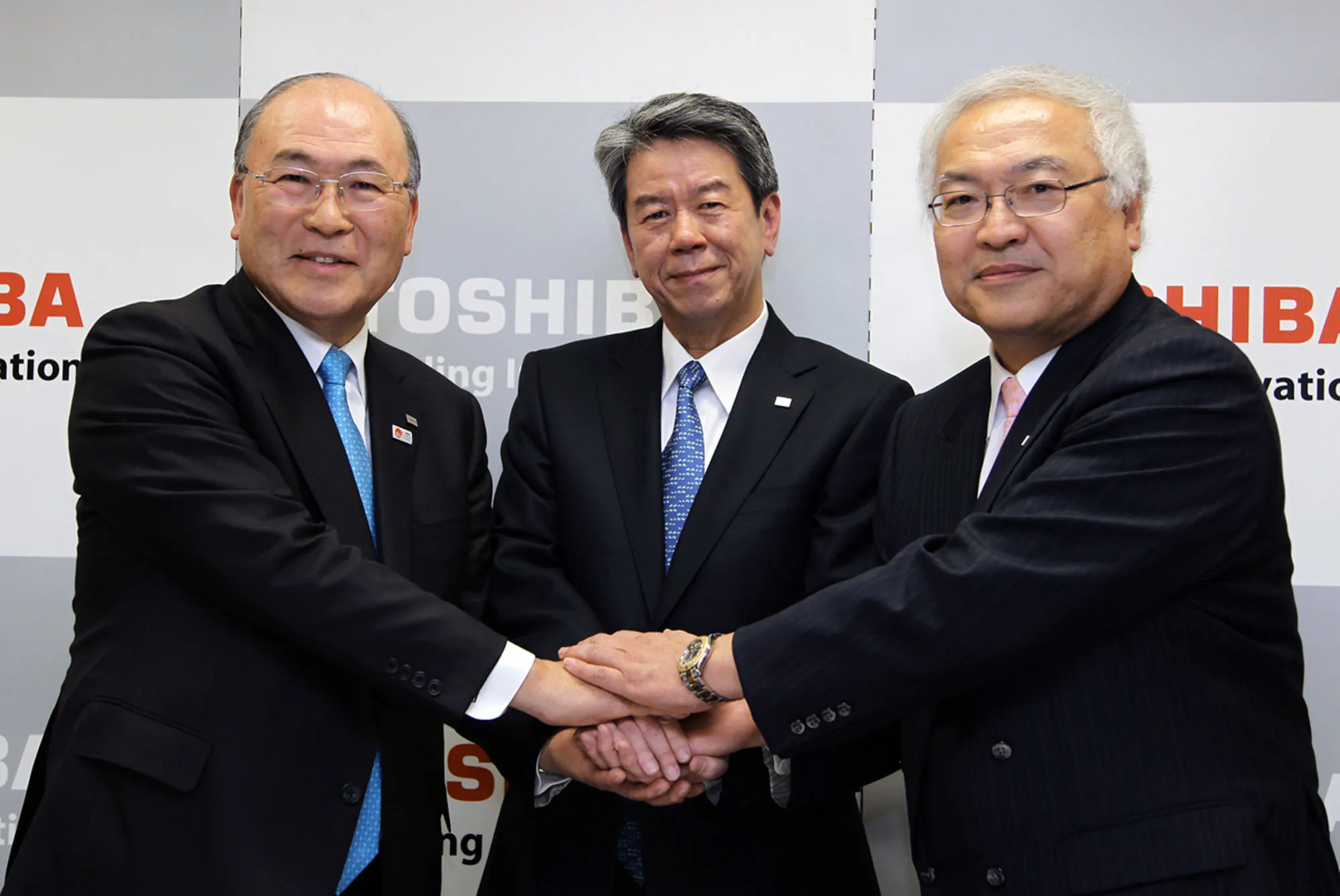 Atsutoshi Nishida, chairman of Toshiba Corp., from left, Hisao Tanaka, corporate senior executive vice president, and Norio Sasaki, president and chief executive officer, shake hands at a news conference in Tokyo.
