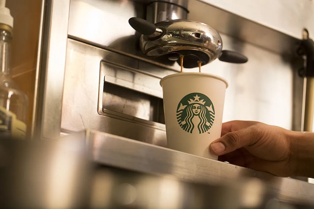Coffee pours from a coffee machine into a cardboard coffee cup inside a Starbucks Corp. coffee shop in London, U.K., on Monday, June 9, 2014. U.K. services companies' confidence rose to a record this quarter, indicating continued expansion in the largest part of the economy, the Confederation of British Industry said.