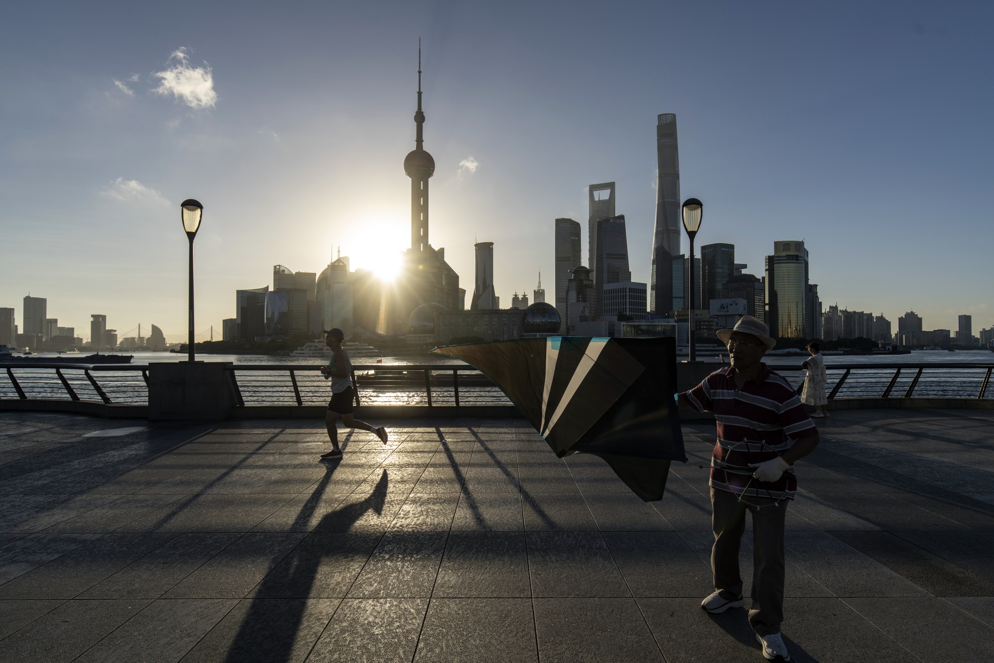 Pedestrians along the Bund across from commercial buildings in Pudong's Lujiazui Financial District in Shanghai, China, on Friday, Sept. 13, 2024. China’s central bank has announced a sweep of support for the economy, as pressure mounts on authorities to unleash stimulus and hit this year’s growth target of around 5%.