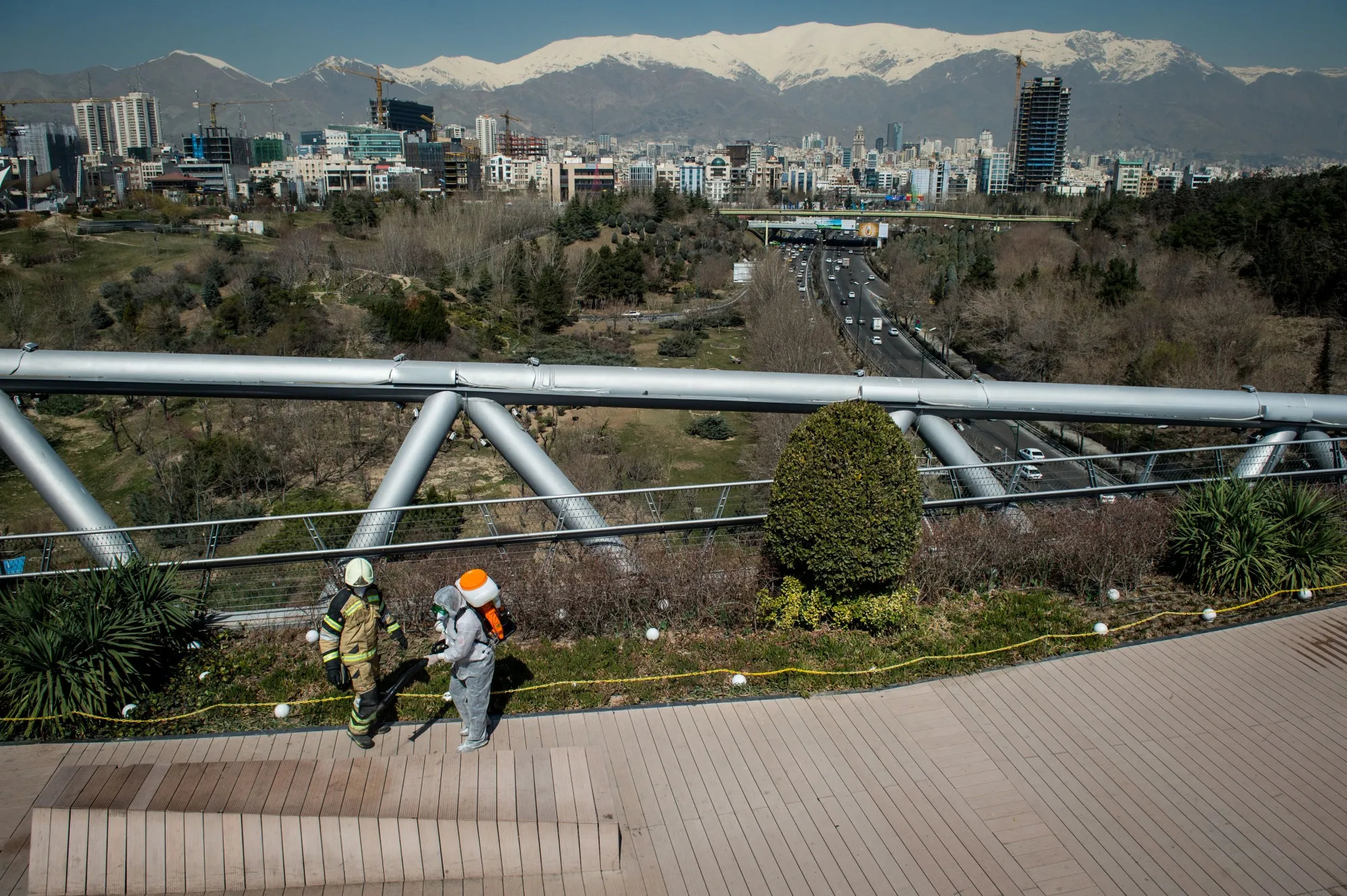 A firefighter wearing protective clothing, mask and goggles, sprays disinfectant on Tabia't bridge pedestrian overpass near the Modarres expressway in Tehran, Iran.&nbsp;
