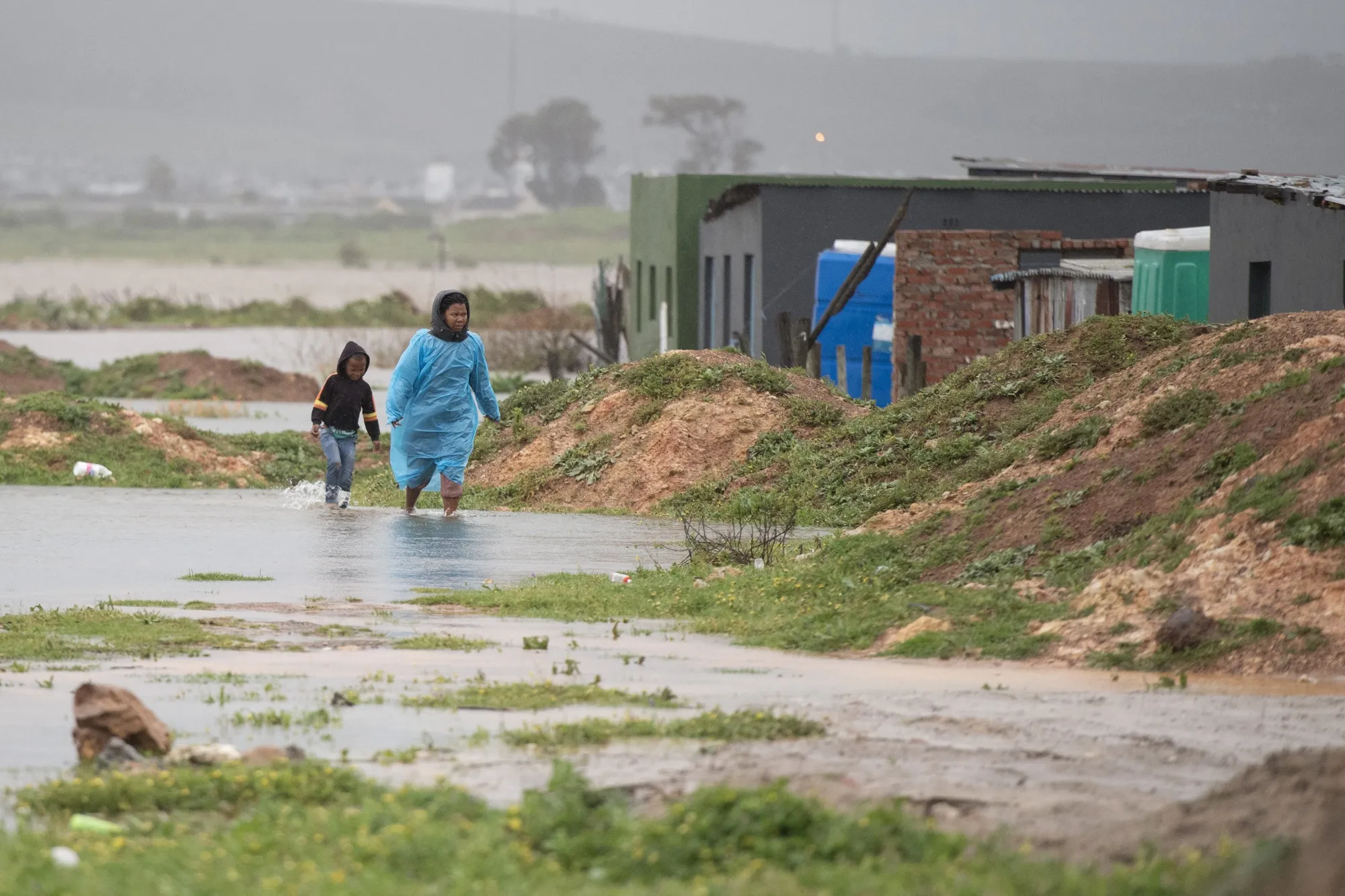 People walk through water and mud during heavy flooding near&nbsp;Somerset West, South Africa, in September 2023.
