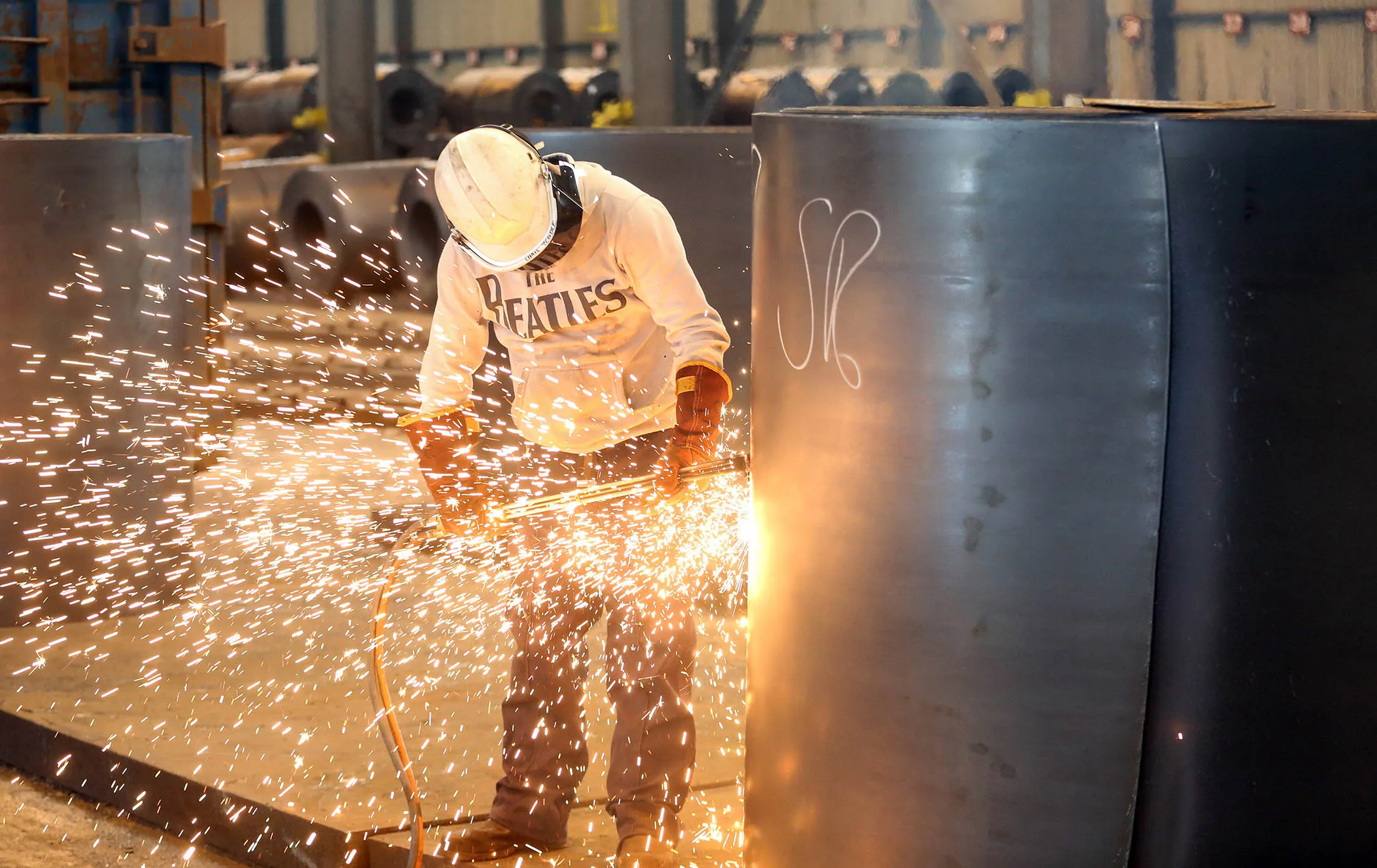 An employee cuts a sample from a roll of coiled steel inside Liberty House Group's rolling steel mill in Newport, U.K., on Tuesday, May
