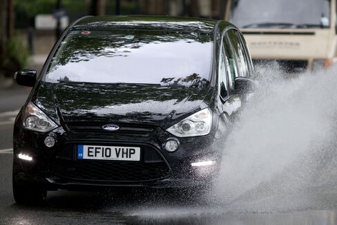 A car drives through a large puddle left after heavy rain in central London, England, on July 8, 2012.