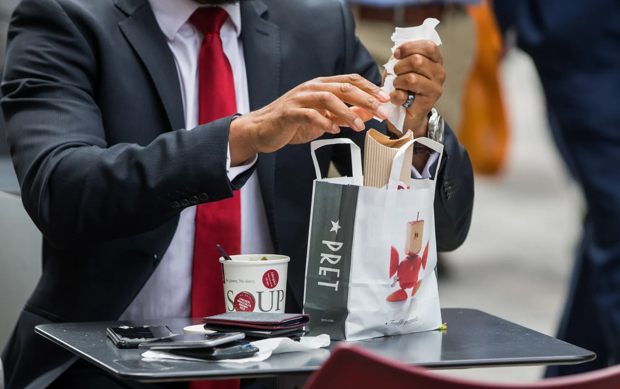 A customer removes the contents of a bag outside a branch of Pret A Manger Ltd. sandwich shop in London.