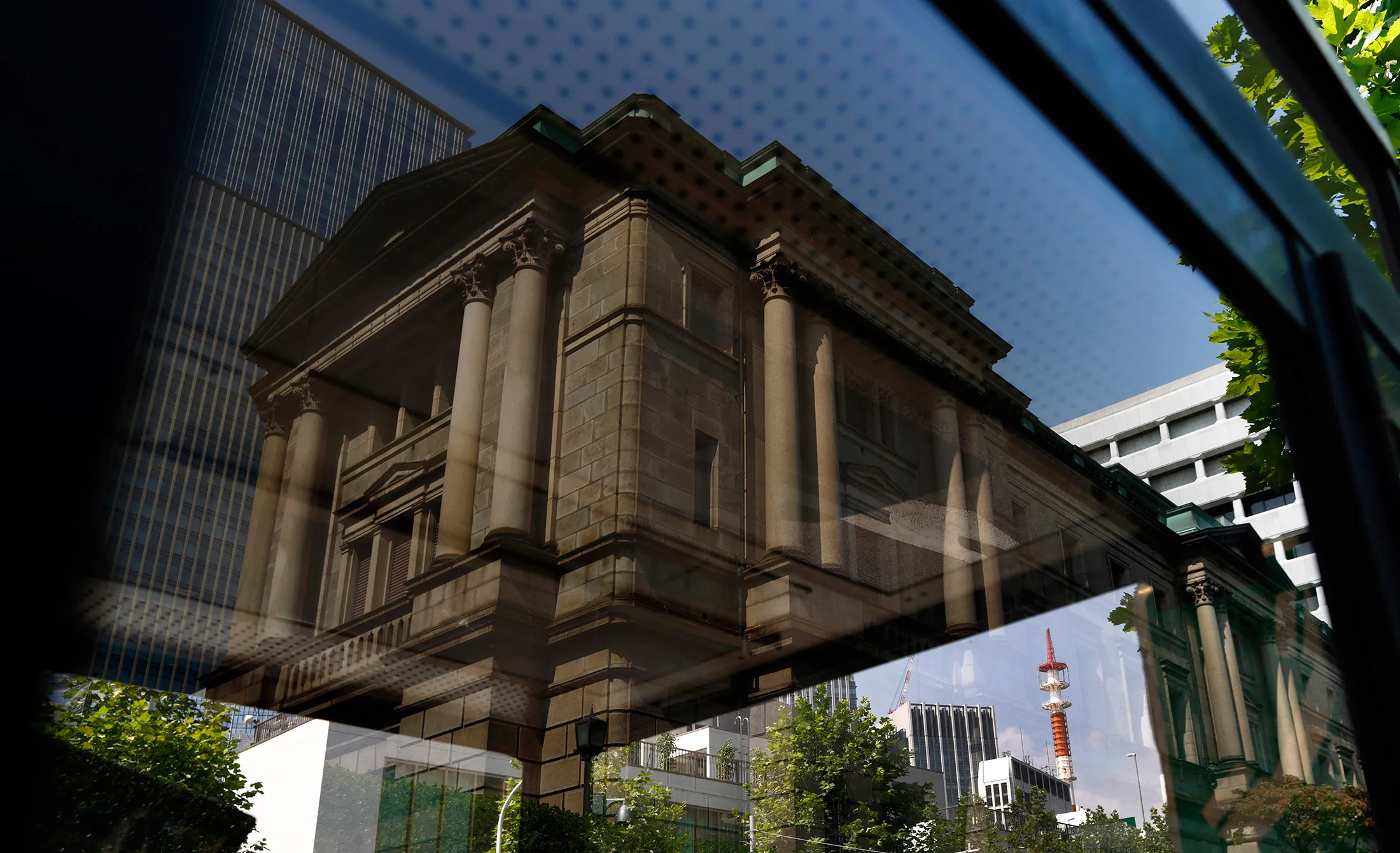 The Bank of Japan headquarters is reflected on a telephone booth window in Tokyo, Japan.
