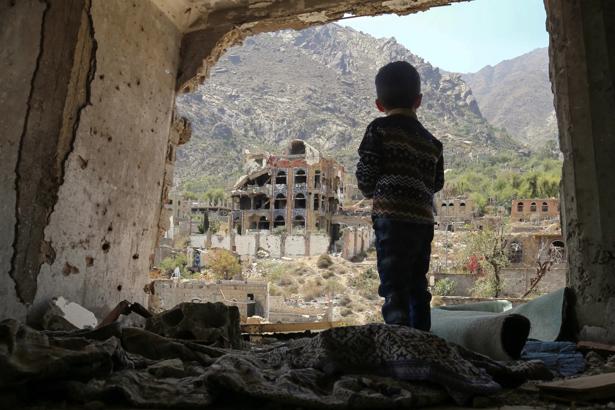 A Yemeni child looks out at damaged buildings from&nbsp;an air strike in Taez, Yemen.&nbsp;