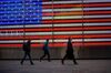 Pedestrians walk past an illuminated American flag in the Times Square area of New York, U.S., on Friday, April 26, 2019. U.S. stocks edged higher on better-than-forecast earnings while Treasury yields fell after data signaled tepid inflation in the first quarter.