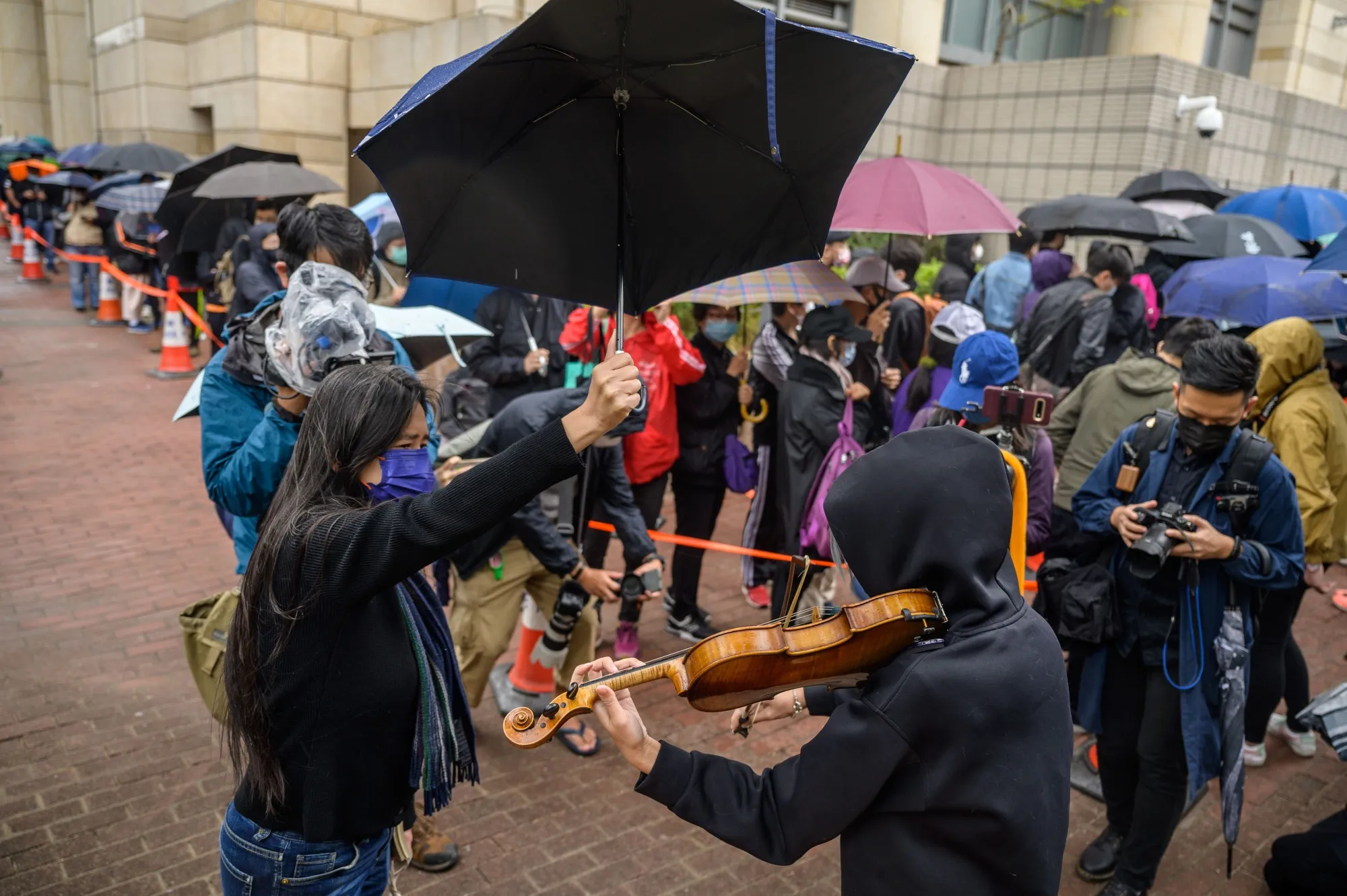A supporter plays a violin as others line up outside West Kowloon court on March 4.
