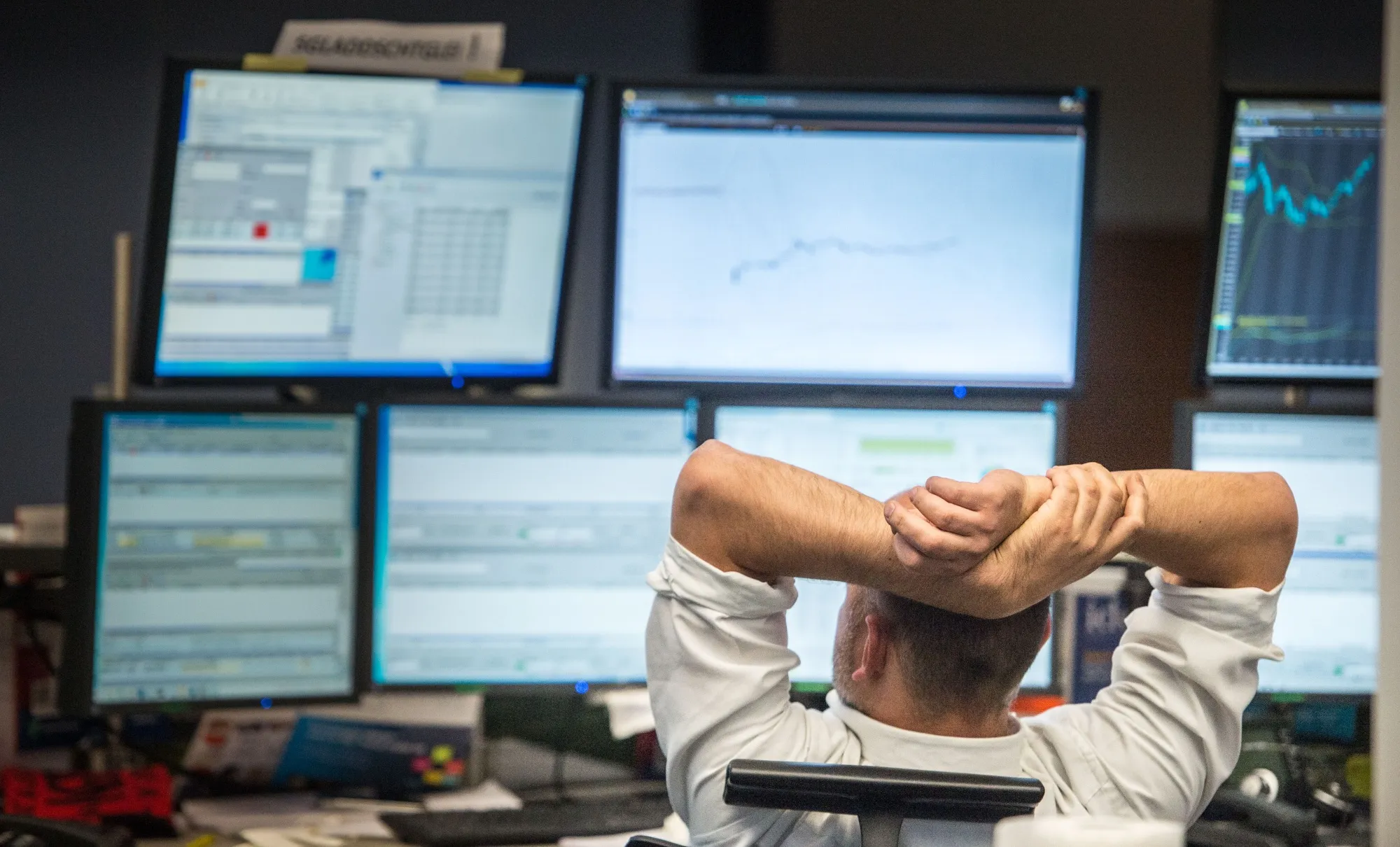 A trader looks at computer screens displaying the&nbsp;stock market index.&nbsp;